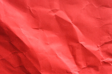 Full frame abstract background of crumpled dark red paper texture with diagonal folds and creases. Represents stress, anger, emotion, abstract surface, grunge, and dramatic concept.