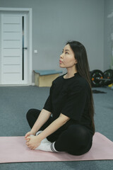 Young Asian woman is stretching yoga workout on exercise mat in sport room.