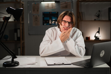 Portrait of male doctor feeling painful toothache working on night shift in hospital. Teeth problem tooth pain. Dental healthcare