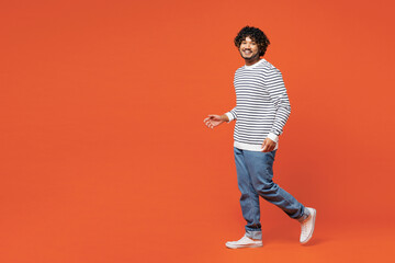 Full body side view young smiling fun happy Indian man he wear striped sweatshirt casual clothes...