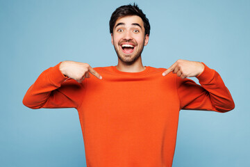 Young shocked surprised man he wearing orange sweatshirt casual clothes point index finger down...
