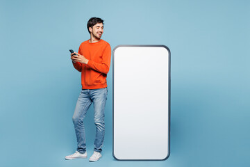 Full length young fun man he wearing orange sweatshirt casual clothes big huge blank screen mobile...