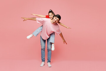 Full body young parent man with child girl wearing red casual clothes Daddy little kid daughter give piggyback ride to joyful, sit on back isolated on plain pink background. Father's Day Love concept
