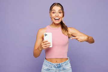 Young happy amazed woman wear pink tank top casual clothes hold in hand use point index finger on...