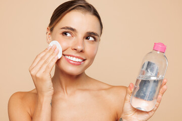 Beautiful half naked topless young woman 20s with nude make up use micellar water clean face...