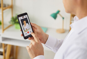 Closeup of a person using a smartphone dating app, tapping the heart icon to like a user's profile in a living room, showing screen and finger interaction. Find love and online dating concept.