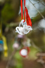 Colorful pacifiers hang cheerfully on ribbons in a tranquil forest setting during spring afternoons, creating a whimsical and playful atmosphere