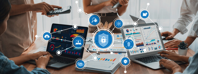 Professionals engage in collaborative discussions on digital security, utilizing laptops and data charts in a contemporary office space for effective decision-making. Amity