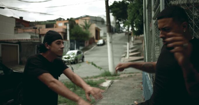 Hispanic men pushing each other in heated street argument near fence, physical altercation escalating with visible anger and emotion, expressing conflict, dominance, and confrontation
