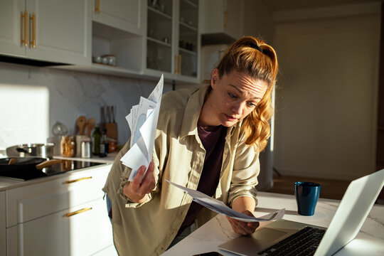 Young adult woman managing bills in kitchen