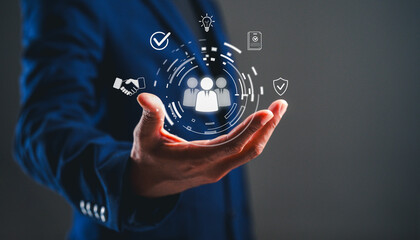 A business professional holds a hand with digital icons representing teamwork, communication, and...