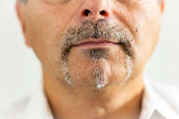 Detailed close-up of a mature man’s lower face showing a distinctive gray mustache and goatee. The photograph captures natural skin texture and hair detail in sharp focus.