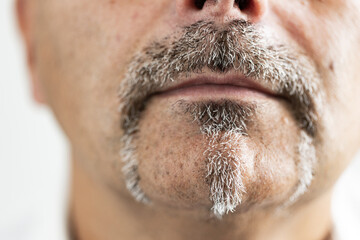 Macro close-up of a man’s mouth and beard showing detailed texture of gray facial hair. The image captures authenticity, and character, perfect for illustrating themes of masculinity while aging.