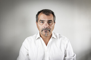 Studio portrait of a middle-aged man with salt-and-pepper hair, mustache, and goatee wearing a white shirt.