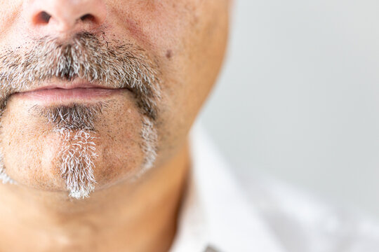 Close-up portrait of the lower half of a mature man's face, showcasing a unique and well-groomed facial hairstyle.