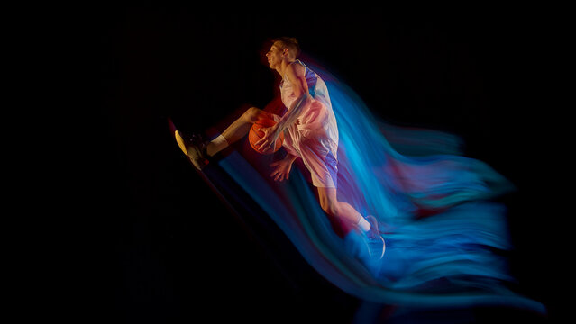 Basketball player flying midair with ball and blue motion streaks showing athletic power. Concept of personal growth, sports education, health promotion, and inspiring freedom style.