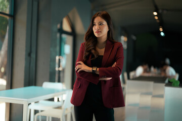 Asian businesswoman with arms crossed standing in modern office