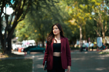 Asian woman walking outdoors carrying laptop computer