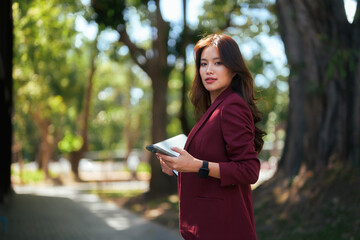 Asian businesswoman using tablet and phone in park