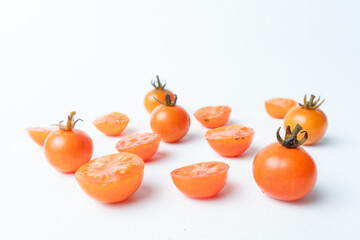 Fresh cherry tomatoes, whole and sliced, scattered on a clean white background. Minimalist food concept with ample copy space. Healthy ingredients.
