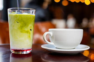 Matcha Latte and Coffee Cup on Café Table with Warm Lights