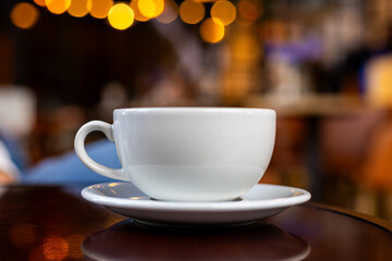 White Coffee Cup on Wooden Table with Warm Bokeh Lights
