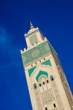 Tower of a mosque intricately decorated with geometric patterns against a clear blue sky. Casablanca, Morocco
