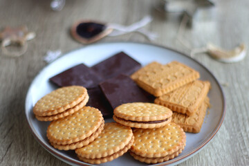 Various Christmas decorations, cookies, chocolate and nuts on wooden background. Selective focus.