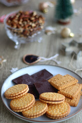 Various Christmas decorations, cookies, chocolate and nuts on wooden background. Selective focus.