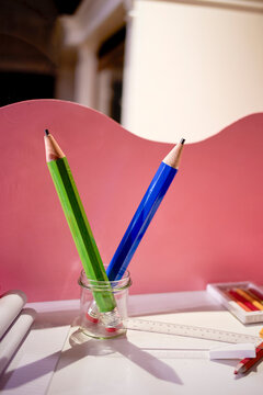 Two oversized pencils stand in a jar on a pink partitioned desk. Blankenberge, West Flanders, Belgium
