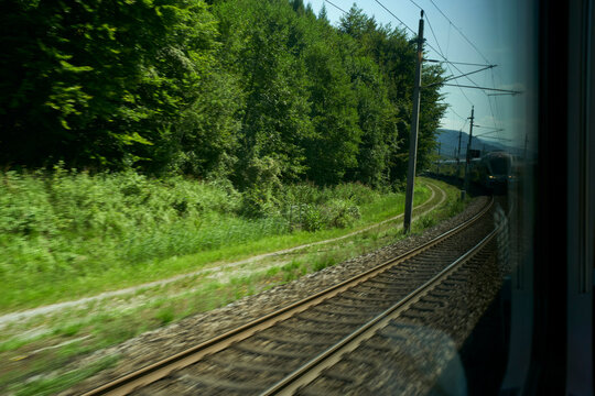 Fototapeta Train tracks winding through lush green forest viewed from a window Salzkammergut, Salt Domain, Dachstein Mountains, Austria