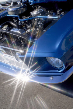 Close-up of a classic blue car engine with gleaming metal parts and lens flare effects. Tokyo, Japan