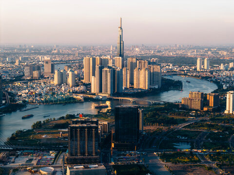 Aerial view of a city skyline with tall modern skyscrapers and a winding river at sunset. Ho Chi Minh City, Vietnam