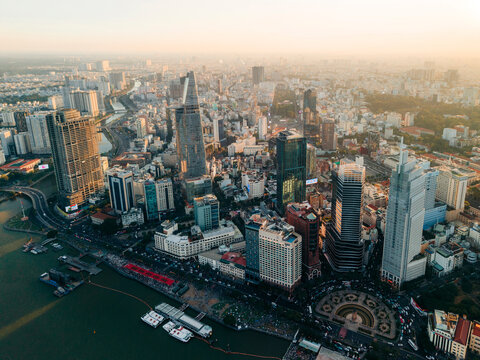 Aerial view of a bustling cityscape with tall skyscrapers at sunset near a river. Ho Chi Minh City, Vietnam