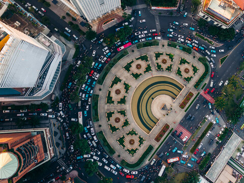 Aerial view of a bustling city intersection surrounding a large circular park with fountains. Ho Chi Minh City, Vietnam