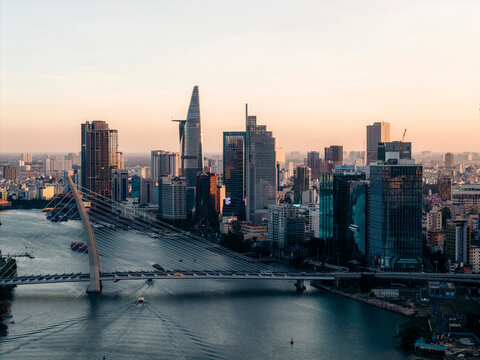 Sunrise view of a modern city skyline with tall skyscrapers and a river bridge. Ho Chi Minh City, Vietnam