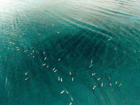 Aerial view of numerous surfers on calm turquoise ocean waters forming a captivating pattern. Lombok, Tanjung Ann, Indonesia