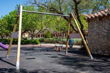 playground swings while surrounded by green trees and cheerful atmosphere on bright sunny day