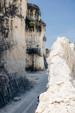 Narrow path between towering rocky cliffs under a clear blue sky. Madura, East Java, Indonesia
