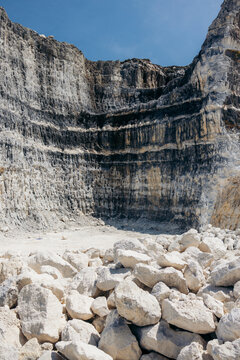 Rugged quarry walls with scattered white rocks under a clear blue sky. Madura, East Java, Indonesia