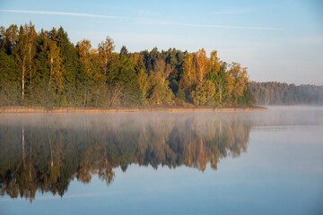 Fototapeta premium autumn landscape, lake shore, morning by the lake, colorful trees reflecting in the lake water, Vaidava Lake, Latvia
