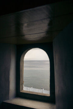 View of calm sea through an arched window, framed by dark walls in a serene setting. Ambon, Maluku, Indonesia