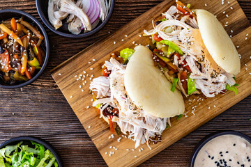 Bao Buns with pulled chicken and vegetables on wooden table. Top view