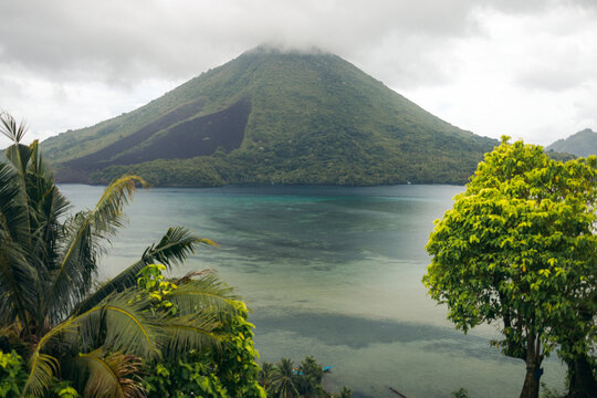 Lush tropical landscape with a misty mountain and serene blue waters. Banda Neira, Banda, Central Maluku, Indonesia