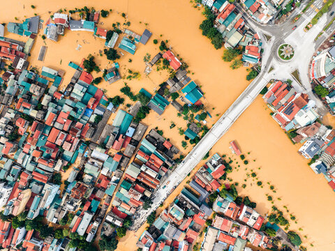 Aerial view of a flooded city with submerged roads and colorful roofs surrounding a bridge. Cao Bang city, Cao Bang, Vietnam