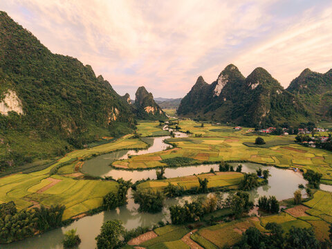 Lush green valley with a winding river surrounded by dramatic mountains under a soft sky. Phong Nam, Tr˘ng Kh&middot;nh District, Cao Bang, Vietnam