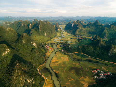 Aerial view of verdant mountains and river winding through patchwork fields and villages. Phong Nam, Tr˘ng Kh&middot;nh District, Cao Bang, Vietnam