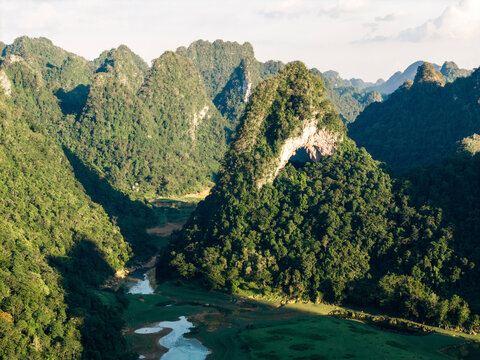 Aerial view of lush green mountains with a winding river under a partly cloudy sky. God?s Eye Mountain, Cao Chuong, Tr˘ng Kh&middot;nh District, Cao Bang, Vietnam