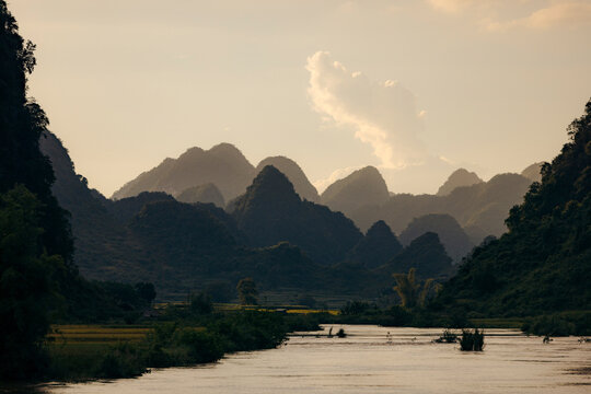 Serene mountainous landscape with a river under a soft, cloudy sky at sunset. Phong Nam, Tr˘ng Kh·nh District, Cao Bang, Vietnam