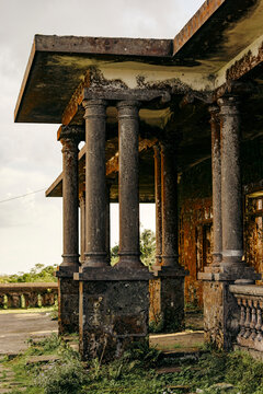 Weathered stone columns of an abandoned building with a mossy, overgrown exterior. Loc B&Iuml;nh District, Lang Son, Vietnam